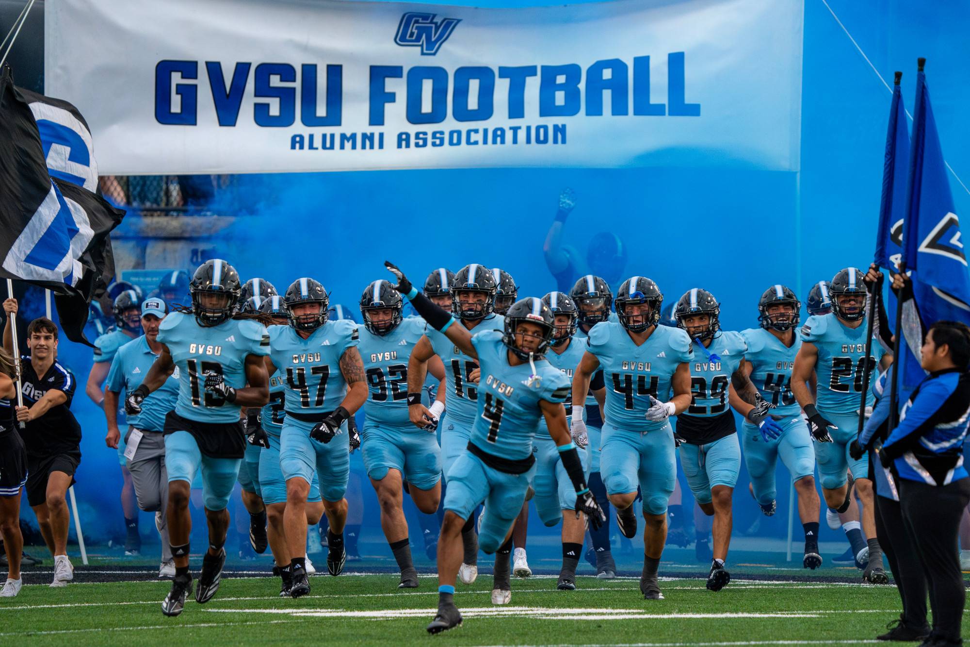 GVSU Football team runs into Lubbers Stadium with blue smoke